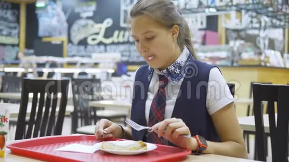 穿着校服的少女坐在学校食堂的桌子旁吃东西视频的预览图