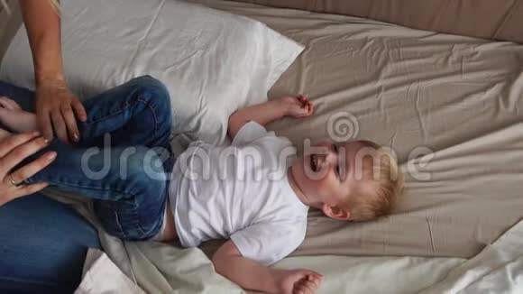 妈妈挠了挠躺在床上的男孩他直视着摄像机大声笑视频的预览图