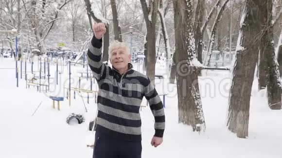 一位欧洲老人在冬天做早晨的户外热身锻炼肩膀热身健康生活视频的预览图