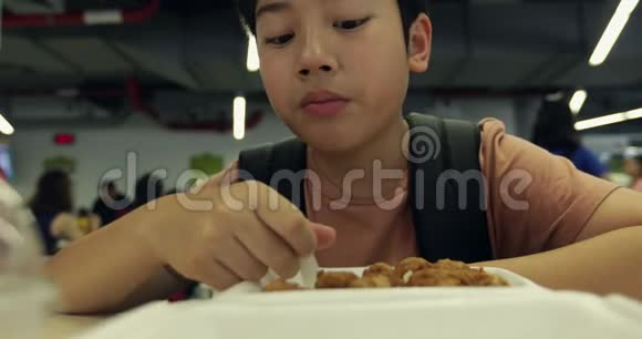 小亚洲男孩在食堂餐厅吃肉球和米饭小亚洲小孩吃肉球炒饭视频的预览图
