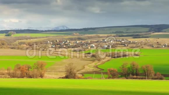 春天的风景黑雨云和绿色草地阳光下的村庄视频的预览图