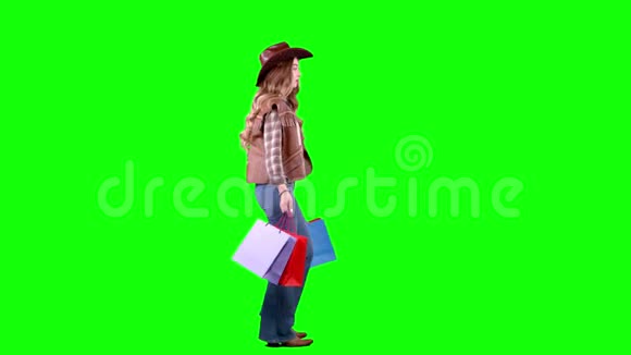 戴着帽子和牛仔靴的女孩手里拿着袋子绿色屏幕侧视图视频的预览图