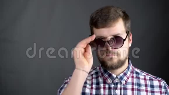 一个穿格子衬衫的男人在摄影棚里戴着眼镜和摘下眼镜视频的预览图