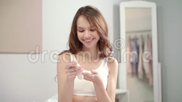 微笑的女人在早上涂上沐浴露快乐女人涂奶油视频的预览图