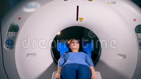 一个女人从CT扫描机的一个开放的环上滑了出来视频的预览图