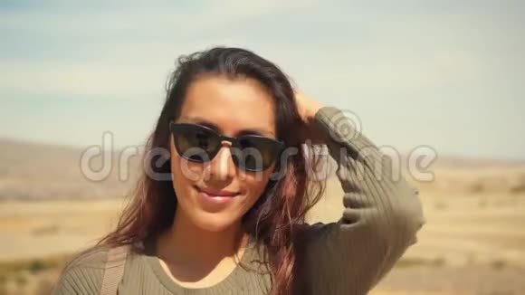 年轻迷人的微笑混合花边女孩肖像在沙漠快乐的女游客在镜头前摇摆在风中摇摆视频的预览图