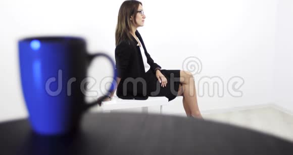 一个穿着商务黑色西装的中年妇女坐在一张白色的桌子上视频的预览图