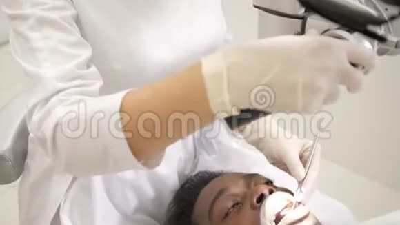 女医生牙医使用显微镜年轻的非裔美国男性病人在牙科诊所的椅子上医学卫生视频的预览图