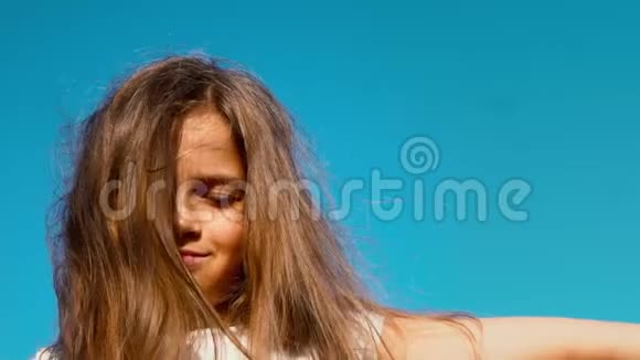 一个长发小女孩的肖像闭着眼睛看着蓝天孩子做梦视频的预览图