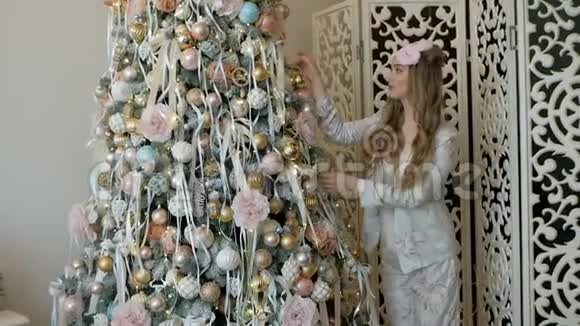 穿着睡衣装饰圣诞树的金发美女视频的预览图