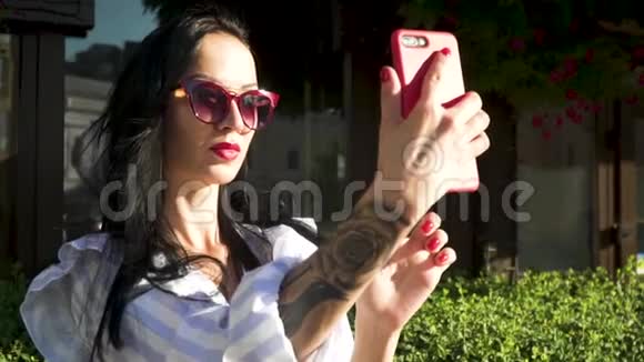 时尚的深色太阳镜手上有纹身在手机上自拍视频的预览图