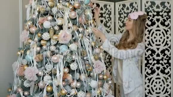 穿着睡衣装饰圣诞树的金发美女视频的预览图