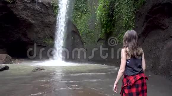 女人举手站在巴厘岛瀑布附近视频的预览图