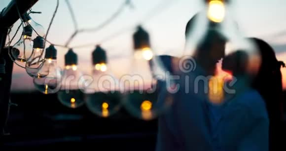 在夕阳西下亲吻的情侣模糊的背景下近距离观看一连串的灯光视频的预览图