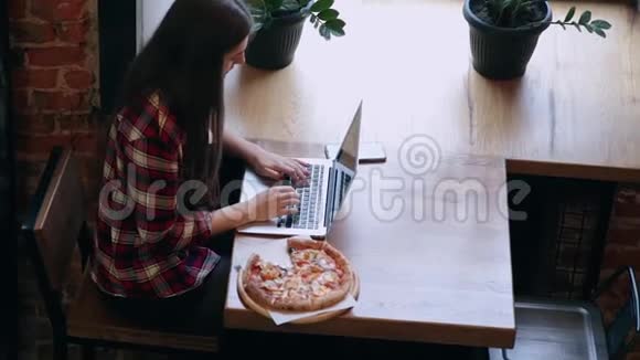 漂亮迷人的商务女性在咖啡馆里的笔记本电脑后面工作桌子上有披萨视频的预览图