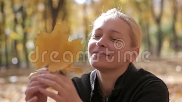 坐在公园里的女人手里拿着枫叶视频的预览图