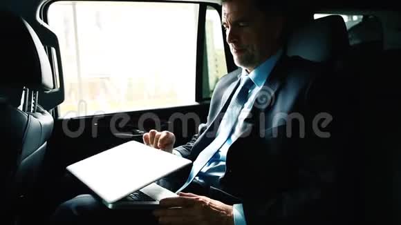 在笔记本电脑上工作的商人骑在汽车后座上视频的预览图