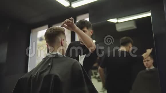 理发师在理发店理发后用喷发剂做发型年轻英俊的高加索男人视频的预览图