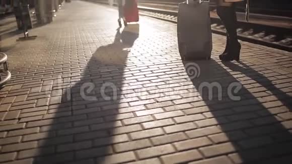 两个女人在火车站的站台上交谈夕阳的灯光和人行道上人的影子视频的预览图