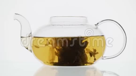 白色背景玻璃茶壶里放着鲜花的异国绿茶视频的预览图