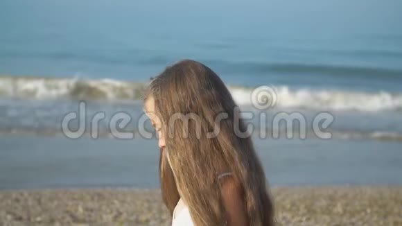 穿着白色裙子的小女孩走在海边视频的预览图