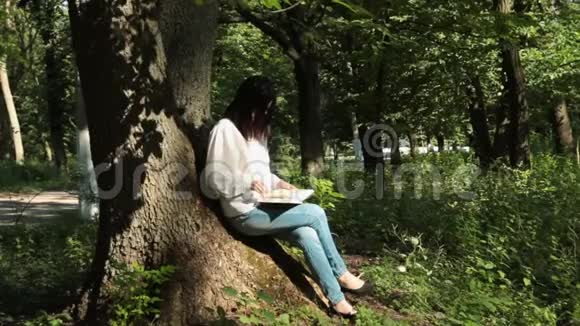 女孩坐在树干上看书视频的预览图