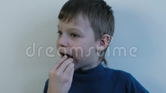 七岁的男孩穿着一件蓝色衬衫把一整块巧克力放进嘴里咀嚼视频的预览图