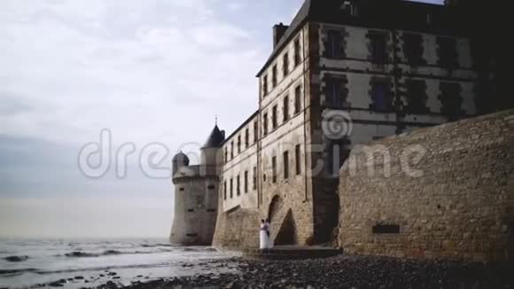 几个中世纪的海岸要塞行动美丽的新婚夫妇站在海岸上建造的中世纪石堡视频的预览图