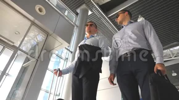 两个年轻的商人站在机场候机楼聊天快乐的白种人商人在视频的预览图