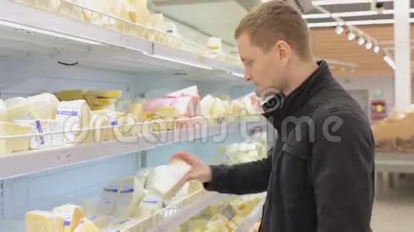 在超市冰箱里选择奶酪的年轻人视频的预览图
