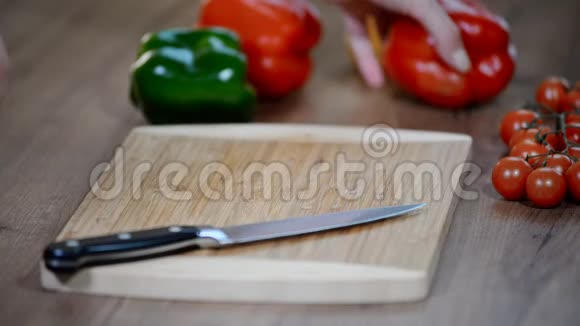 女人手在木切割板上切甜的红钟胡椒视频的预览图