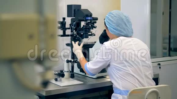 无法辨认的女科学家在现代实验室用显微镜工作视频的预览图