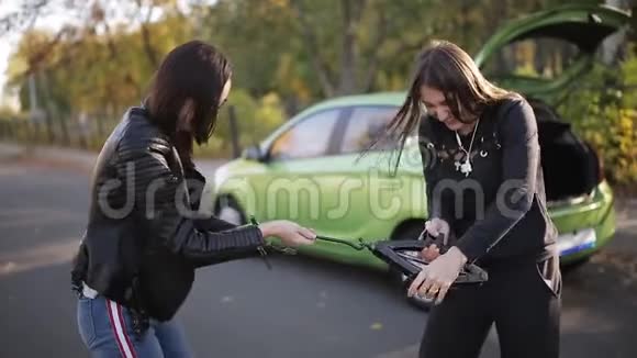两个女人在路边试图用一个杰克从你的车上换轮胎咕哝着视频的预览图