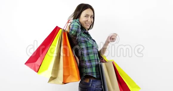 一个快乐的年轻女人手里拿着很多带新衣服的彩色袋子视频的预览图