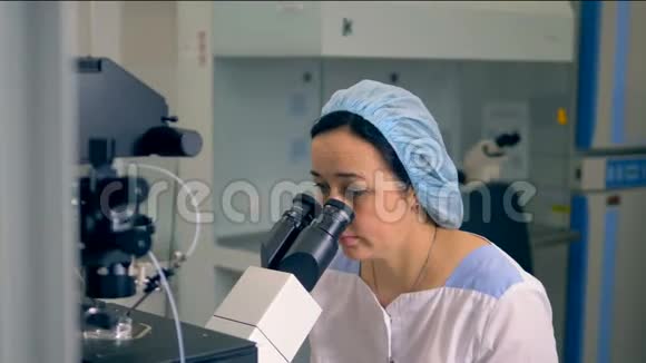 一位女科学家正在通过显微镜观察病毒样本4K视频的预览图