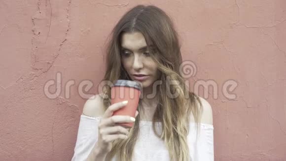 穿着白色毛衣的女人正在喝咖啡去看镜头视频的预览图