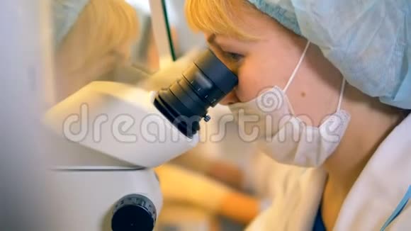 特写一位女科学家在显微镜下观察物体视频的预览图