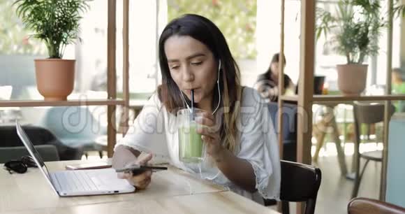 女人喝着健康的绿色冰沙视频的预览图