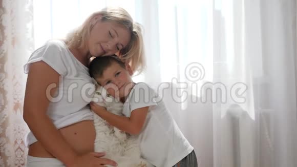 未来的母亲和可爱的男孩手牵着宠物背景是白色窗帘在房间里视频的预览图