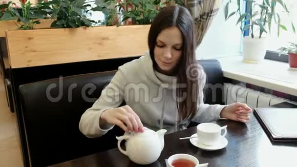 黑发女人打开茶壶闻了闻把茶壶里的茶倒进杯子里视频的预览图