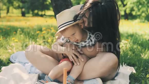 快乐的微笑妈妈和小儿子在大树下野餐家庭概念视频的预览图