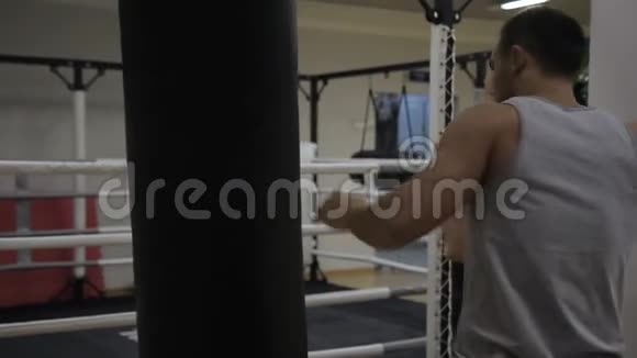 年轻男性拳击手的肖像他正在拳击馆里挂着黑色的拳击袋视频的预览图