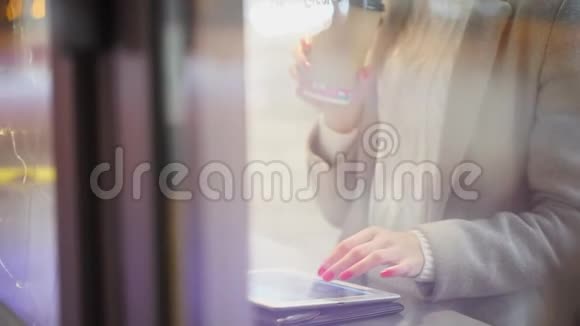 坐在咖啡店里的随便女人女人在咖啡馆里用平板电脑喝咖啡或茶慢动作青年视频的预览图