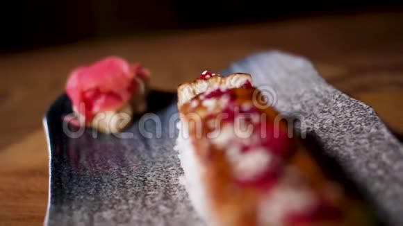 靠近日本寿司卷在一个黑色盘子站在木桌上食品店的概念框架新鲜美味可口视频的预览图