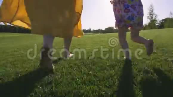 妈妈和女孩赤脚在草地上奔跑视频的预览图