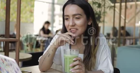 年轻女子啜饮健康的绿色冰沙视频的预览图