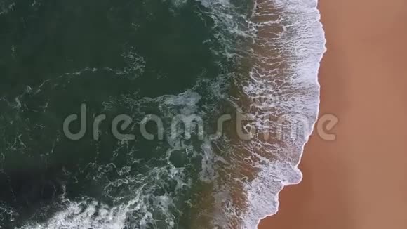 无人驾驶飞机在葡萄牙一个金色海滩的沙滩上看到蓝色海浪视频的预览图