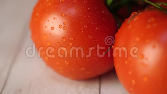 成熟的西红柿和水滴在桌子上成熟的红西红柿有绿色的茎和水滴在木头上视频的预览图