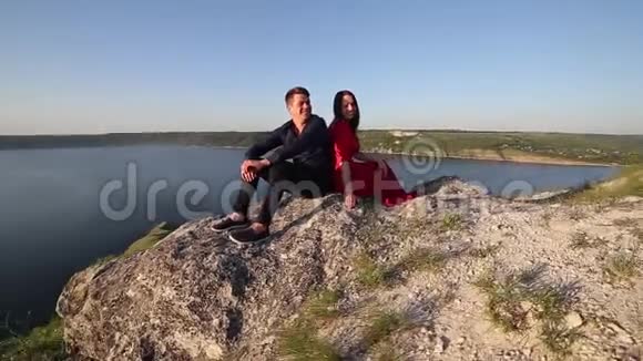 恋爱中的情侣坐在河边日落的光视频的预览图