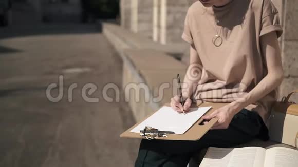 不可辨认的年轻女子在夏日外面用铅笔写字视频的预览图